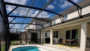 Piscina com hidromassagem, rodeada por um espaço coberto com mobiliário para área externa.