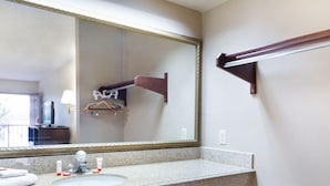 A bathroom with a granite countertop sink, a large mirror with a gold frame, and a towel rack. - Days Inn & Suites by Wyndham Brewton (Brewton)