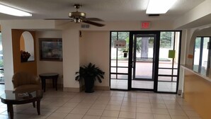 A lobby with a ceiling fan, a door marked 'EXIT,' a framed picture on the wall, and a potted plant. - Days Inn & Suites by Wyndham Brewton (Brewton)