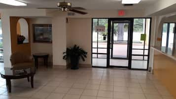 A lobby with a ceiling fan, a door marked 'EXIT,' a framed picture on the wall, and a potted plant.