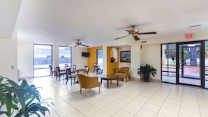 A spacious lobby with ceiling fans, a reception desk, and a view of the city through large windows. - Days Inn & Suites by Wyndham Brewton (Brewton)
