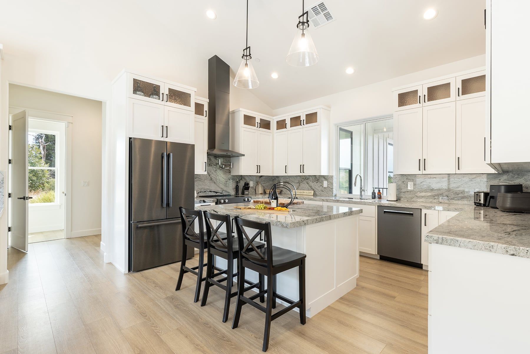 A modern kitchen with a central island, stainless steel appliances, and a large window.