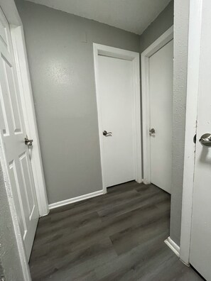 A hallway with two white doors, grey walls, and a wooden floor.