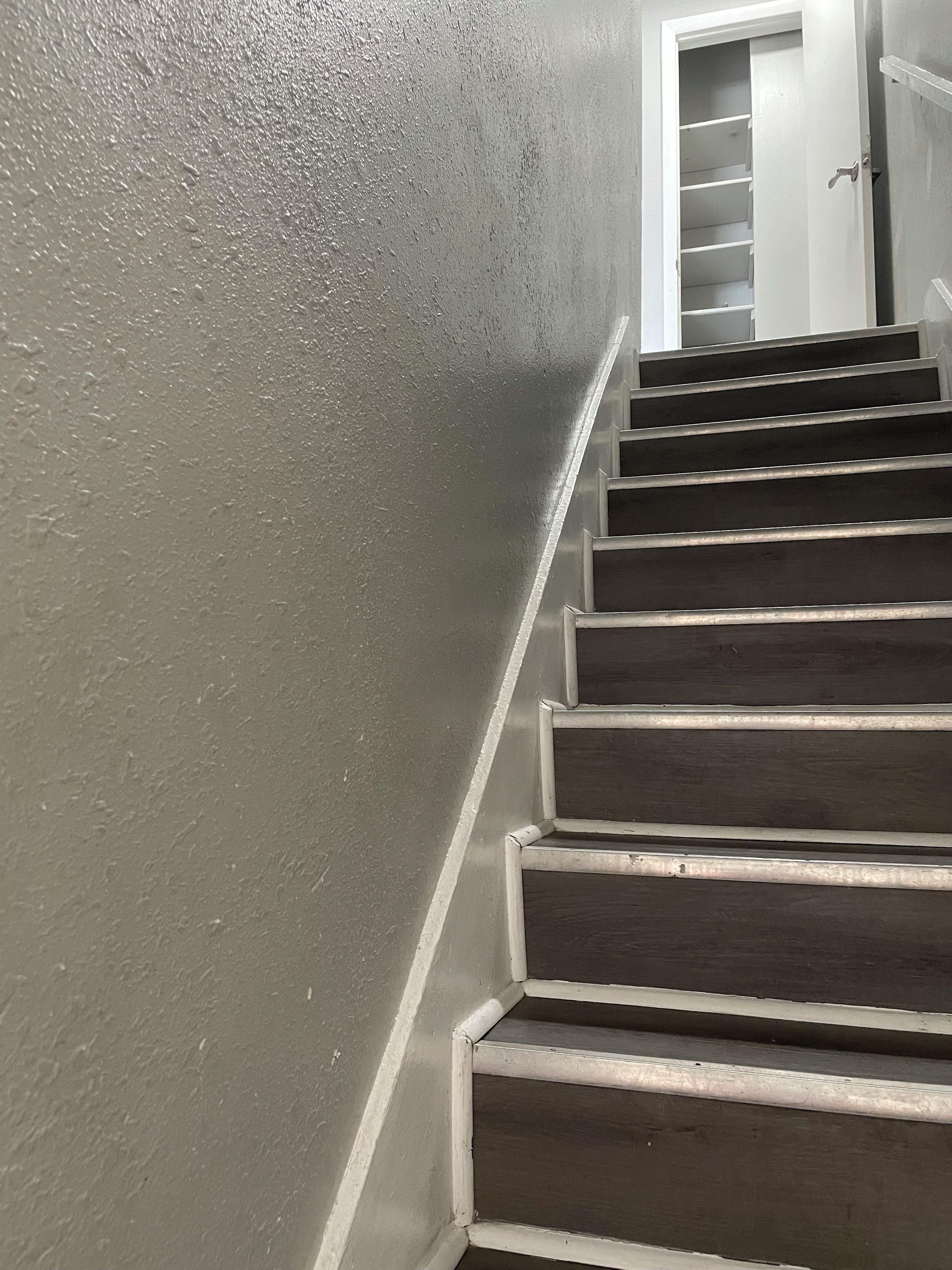 Een trap met een gestructureerde muur aan de ene kant en een deur aan de bovenkant.