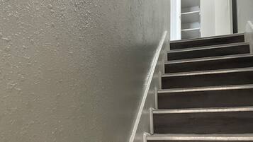 Een trap met een gestructureerde muur aan de ene kant en een deur aan de bovenkant.