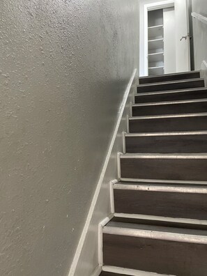 A staircase with a textured wall on one side and a door at the top.