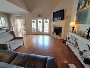 Una sala de estar amplia con chimenea, un sofá y un televisor montado encima.