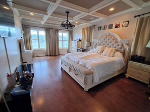 Un dormitorio amplio con una cama grande, un aparador, un tocador y una ventana con cortinas.