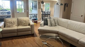 Un salon comprenant deux canapés, une table basse en verre et un coin repas avec des chaises et une table.