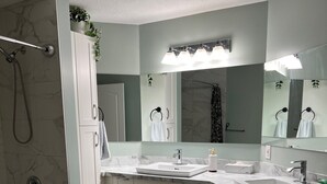 Une salle de bain moderne équipée d’une baignoire, de deux lavabos, de toilettes et d’une douche.