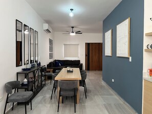 Una sala de estar moderna con sofá, mesa de comedor, sillas y un ventilador de techo.