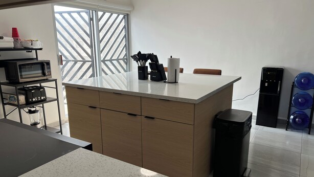 Una cocina moderna con una isla central, microondas, tostadora y dispensador de agua.