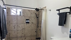 Un baño con ducha, inodoro, lavamanos y toallero.