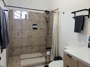 Ein Badezimmer mit Dusche, Toilette, Waschbecken und Handtuchhalter.