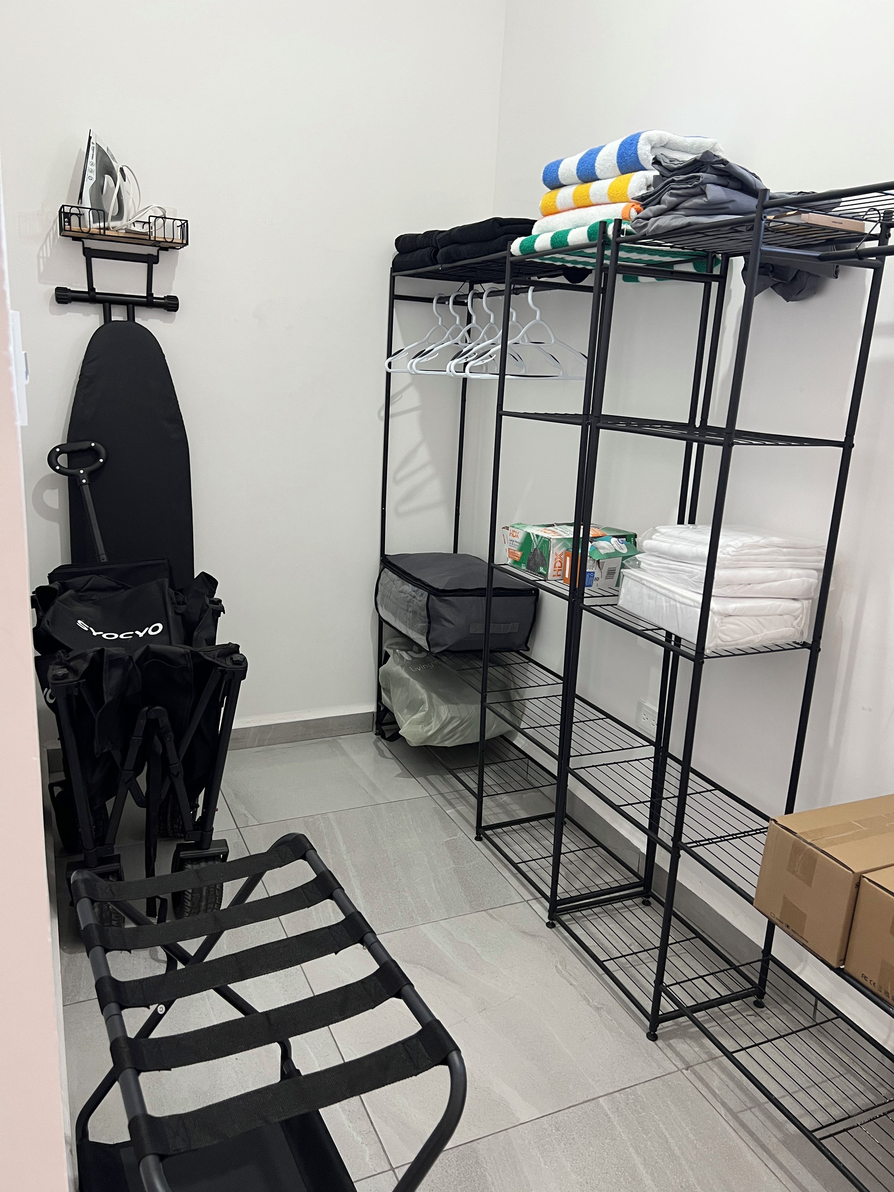 A compact room with a bunk bed, a small ironing board, and a stroller.