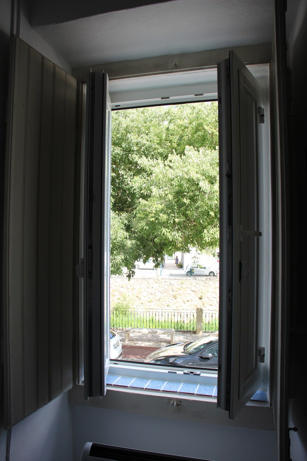 A room with a window, a door, and a view of a tree and a fence.