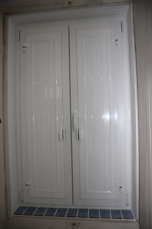 Puerta doble blanca con pomo y una pequeña ventana en la parte inferior.