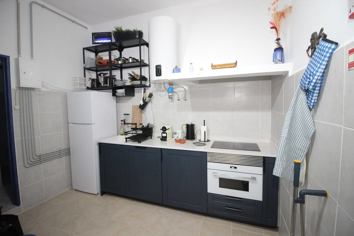 Een kleine keuken met een koelkast, oven en een aanrecht.
