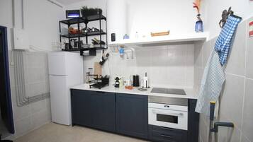 Een kleine keuken met een koelkast, oven en een aanrecht.