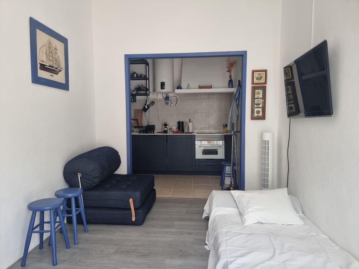 Un espacio habitable compacto con kitchenette, un sofá, una cama y un pequeño comedor.