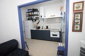 Cuina compacta amb armaris foscos, taulell blanc i una petita zona de menjador amb tamborets.