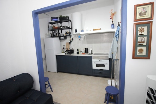 Una cocina compacta con armarios oscuros, una encimera blanca y una pequeña zona de comedor con taburetes.