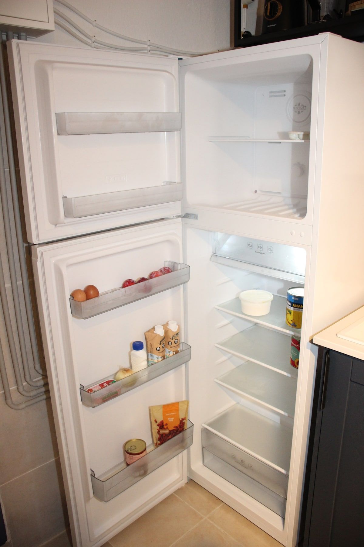 An open refrigerator with shelves containing eggs, milk, and packaged food.