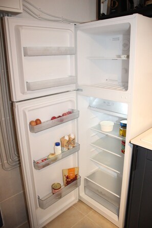 Nevera oberta amb prestatges que contenen ous, llet i aliments envasellats.