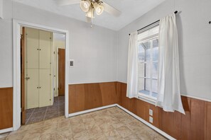 A room with a wooden floor, a ceiling fan, a window with blinds, and a door leading to another room. - 3BR Near White Rock Lake - Fire Pit & BBQ Grill (Dallas)