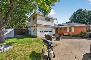 A two-story house with a garage, a patio with outdoor furniture, and a tree in the yard. - 3BR Near White Rock Lake - Fire Pit & BBQ Grill (Dallas)
