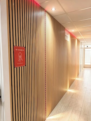 A corridor with vertical wooden slats and a red sign indicating a room with a bed.