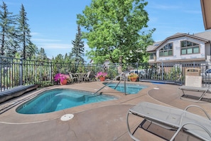 A pool area with two swimming pools, lounge chairs, and potted plants. - Ironwood 16 - 4 Bedroom Ski In Ski Out Next to the Gondolas + EZCancel (Steamboat Springs)