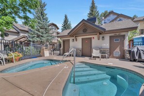 A pool area with two pools, a covered grill, and a building with a door marked 'EXIT'. - Ironwood 16 - 4 Bedroom Ski In Ski Out Next to the Gondolas + EZCancel (Steamboat Springs)
