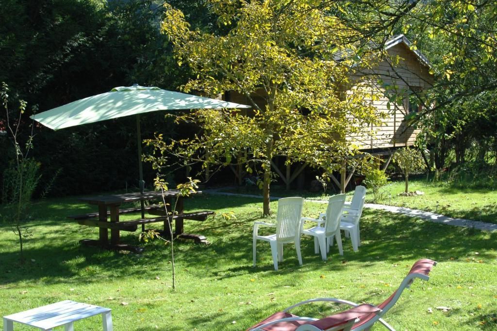 Un espace extérieur aménagé avec une table et des chaises, un parasol et une pelouse.