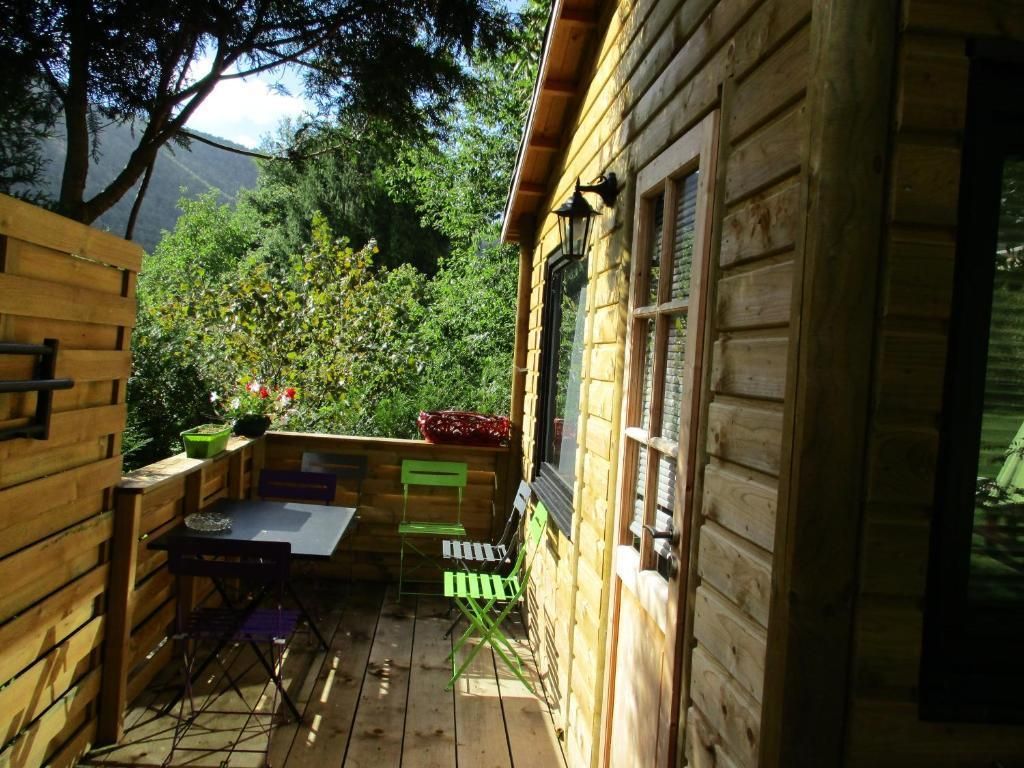 A wooden cabin with a deck, a table, and chairs.