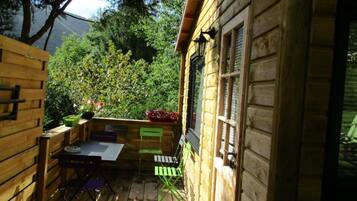 A wooden cabin with a deck, a table, and chairs.