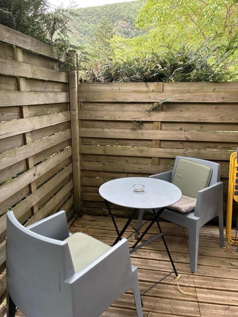 Une terrasse en bois avec une table ronde et deux chaises.