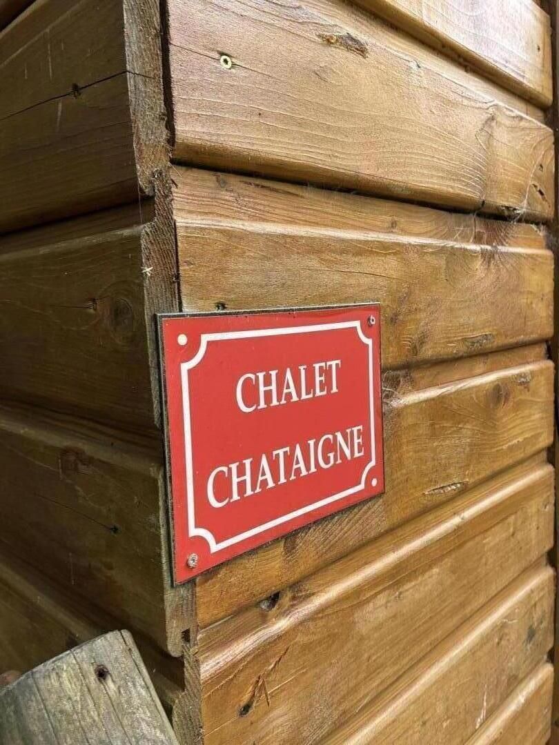 A wooden log cabin with a red sign that reads 'CHALET CHATAIGNE'.