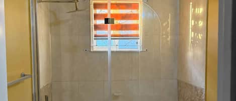 A bathroom with a bathtub, toilet, and a window with blinds.