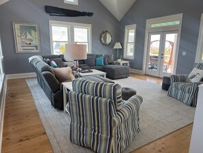 Ein Wohnzimmer mit grauem Sofa, gestreiften Sesseln, einem weißen Couchtisch und einer Lampe.