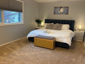 A bedroom with a bed, bedside tables, a bench, a window, and a wall decoration. - Bright & Spotless 3BR plus Free parking Perfect for Families & Long Stays (Calgary)