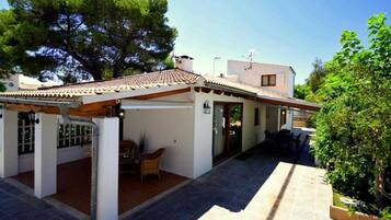 A two-story building with a tiled roof, a covered patio area, and a small garden.