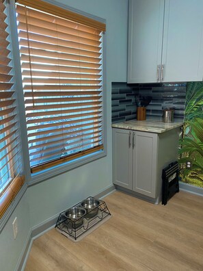 A kitchen with a window, cabinets, a countertop, and a pet feeding station. - Cozy dog friendly studio condo near Lake Hamilton (Hot Springs)