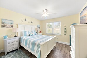 A bedroom with a bed, nightstands, a dresser, a ceiling fan, a window, and wall decorations. - Mariner Lakes 14 Serenity & Sandy Shores (Orange Beach)