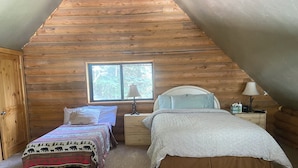 A cozy attic bedroom with two beds, a window, and wooden walls. - Charming cabin in the woods, 1/2 mile to the highway including modern amenities (Durango)