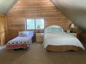 Een gezellig slaapkamer op zolder met twee bedden, een raam en houten wanden.