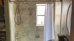 A bathroom with a bathtub, a shower, a window, and a vanity with a mirror. - Charming cabin in the woods, 1/2 mile to the highway including modern amenities (Durango)