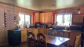 A kitchen with wooden cabinets, a dining table, chairs, a dishwasher, and a microwave. - Charming cabin in the woods, 1/2 mile to the highway including modern amenities (Durango)