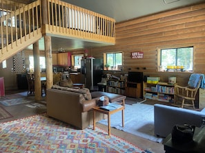 A cabin interior with a living area, kitchen, and a wooden staircase.