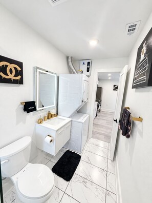 Een moderne badkamer met toilet, wastafel en spiegel.